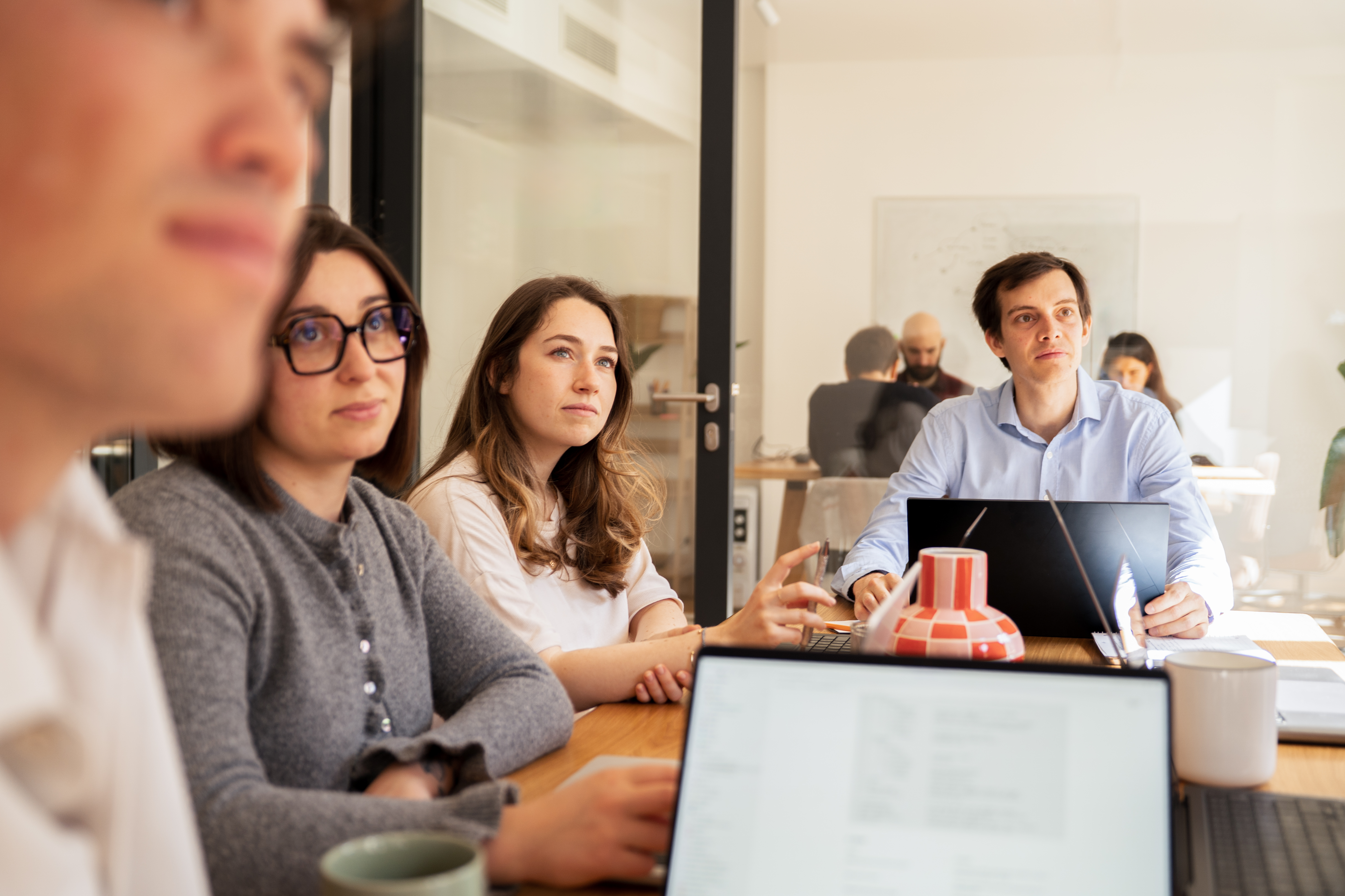 Une équipe Galadrim attentive autour d'une table de réunion, ordinateurs portables ouverts